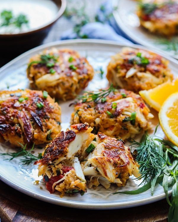 Jumbo Lump Crab Cakes close up – succulent high lump crab-to-breading ratio cakes served with a silky, luscious citrusy sauce. #appetizers #springrecipe #summerrecipe #lightdinners #lightdinnersforsummer #crabcakes #crabcakesrecipe #meyerlemon #chardonnaysauce #winesauce #giveitsomethyme | giveitsomethyme.com