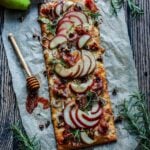 Pear and brie flatbread pizza with prosciutto and rosemary on parchment.