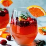 Cranberry orange prosecco cocktail with rosemary in a clear tumbler.
