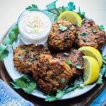Lion's mane mushroom recipe of meatless crab cakes served with yogurt sauce and lemon wedges, and garnished with parsely.