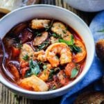 One bowl of shrimp stew served on wooden surface with toasted bread on the side.