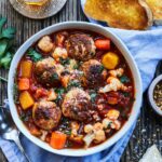 Healthy, tomato-based turkey meatball soup loaded with tender meatballs, squash, cauliflower and carrots served in a white bowl.