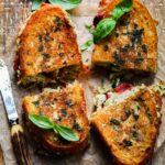 Gooey cheese oozing from Italian grilled cheese sandwich halves with the antique knife used to cut them on the side.