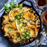 Mexican chicken and tortillas served right from cast iron skillet with forks to the side on a blue napkin.