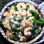 Shrimp asparagus risotto garnished with fresh thyme and basil served in a large bowl on a wooden surface.